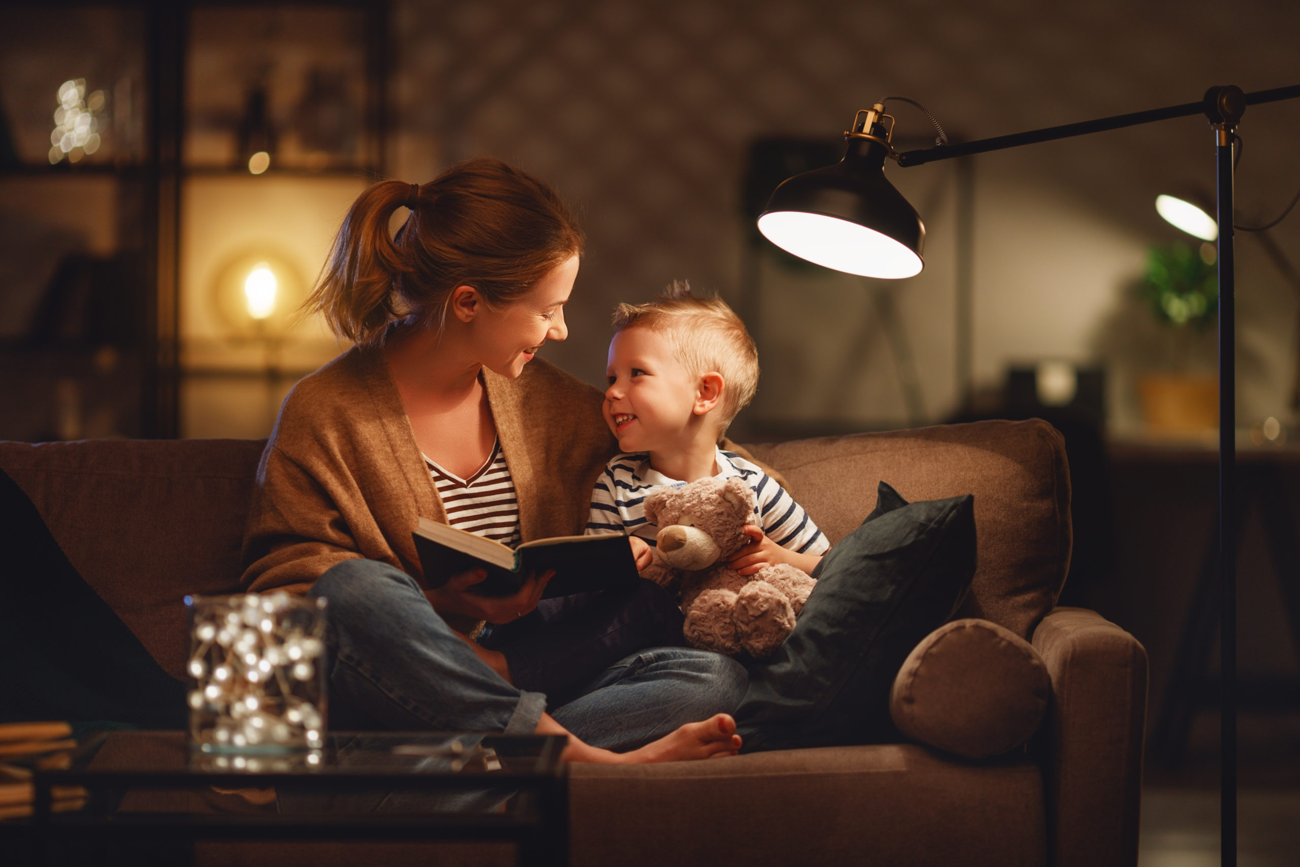 mother and little boy sitting on the sofa reading a book together